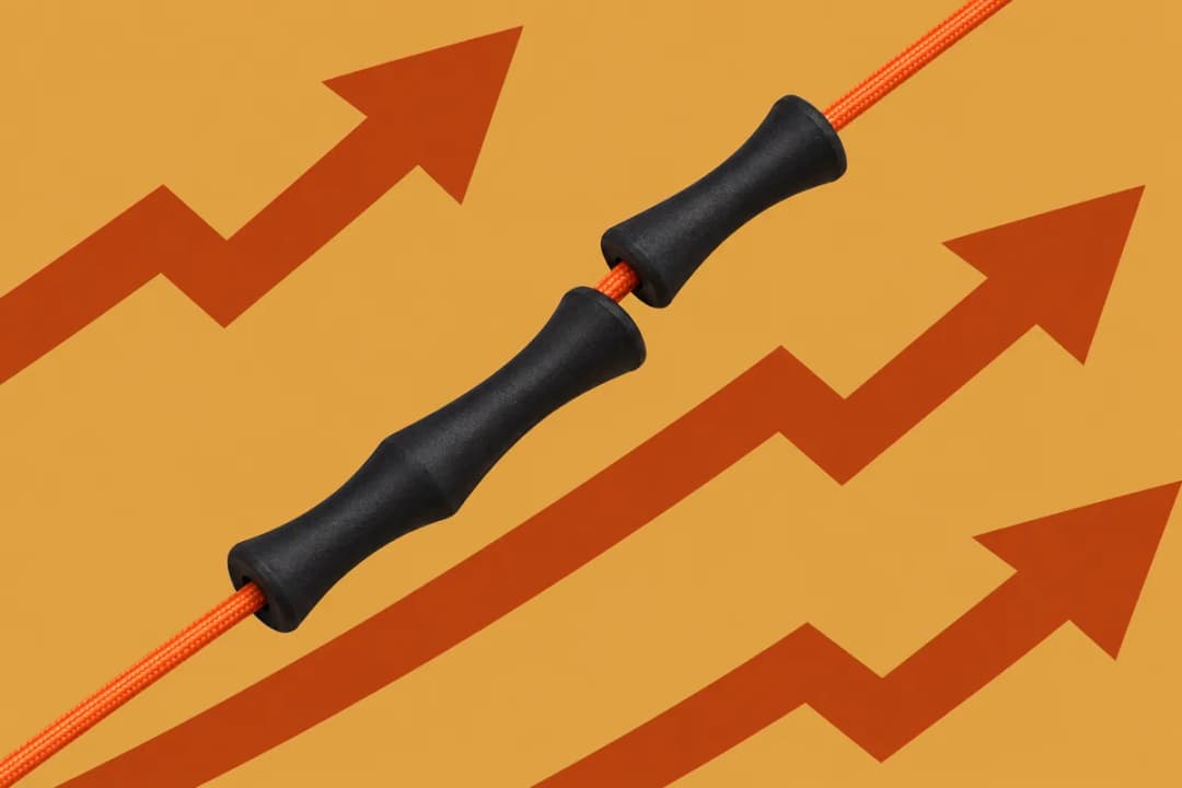 A long and a short black rubber finger saver on one orange bowstring, on a gold background with bold rust zigzag arrows
